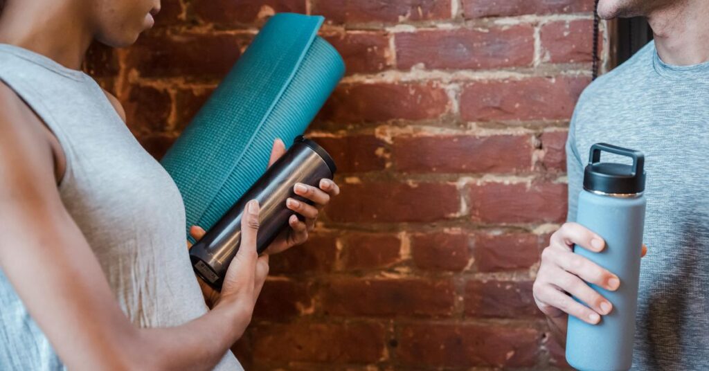 Man and woman holding yoga mat and water bottle preparing for workout highlighting common fitness mistakes after 30