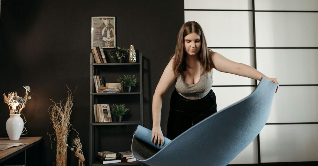 Woman opening yoga mat at home preparing for a simple workout to stay fit after 30 without extreme diets or intense exercise