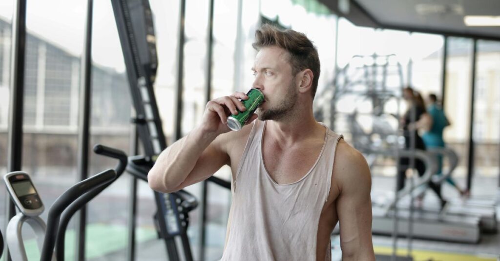 Adult over 30 drinking a generic energy drink in gym setting for pre-workout energy and focus