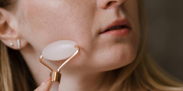 Woman over 30 using a facial massage tool to reduce face fat and improve skin circulation